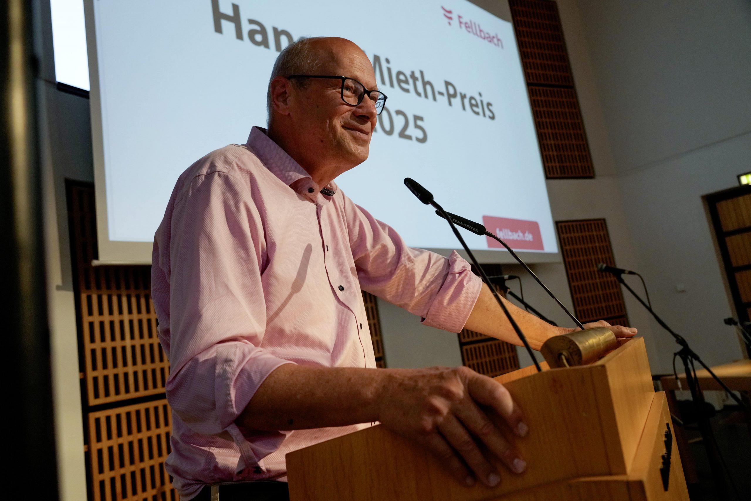 Redner am Rednerpult mit Präsentation im Hintergrund