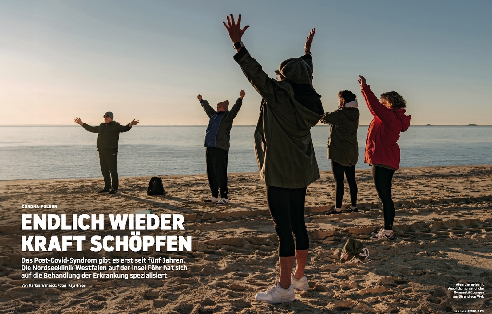 Gruppe am Strand im Sand, die Hände in die Höhe gereckt.